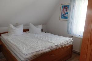 ein Schlafzimmer mit einem Bett mit weißen Laken und Kissen in der Unterkunft FW Lehmann in Zingst