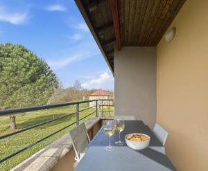 a table with two glasses of wine on a balcony at T3 Piscine Classé 3, Park, Terrasse in Prayssac