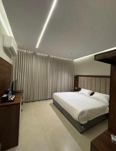 a hotel room with a bed and a television at Milano Hotel in Al-ʿUla