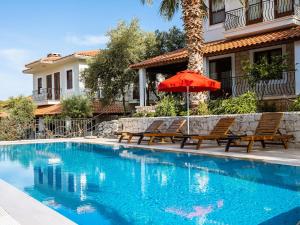 a pool with chairs and an umbrella next to a house at Villa Sarpedon in Kaş