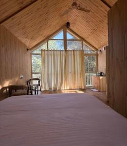 a large bed in a room with a large window at Treehouse by the lake in Bhīm Tāl