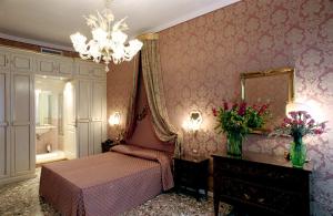 a bedroom with a bed and a mirror and a chandelier at Casa Pisani Canal in Venice