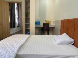 a bedroom with a large white bed and a desk at Love's Hotel in Nhơn Trạch