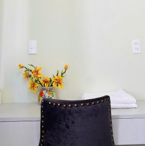 a black chair sitting next to a vase of flowers at Love's Hotel in Nhơn Trạch