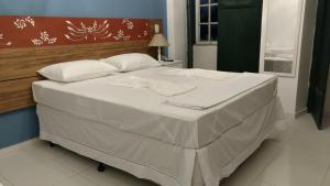 een bed met witte lakens en kussens in een kamer bij Pousada Pai Thomaz in Cachoeira