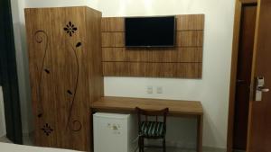 een kamer met een tv en een bureau met een kleine koelkast bij Pousada Pai Thomaz in Cachoeira