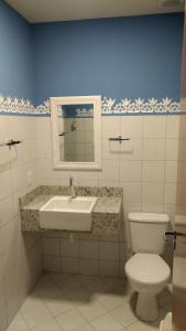 een badkamer met een wastafel, een toilet en een spiegel bij Pousada Pai Thomaz in Cachoeira