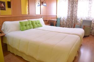 a bedroom with a large white bed with green pillows at Hotel Aro'S in Casas Ibáñez