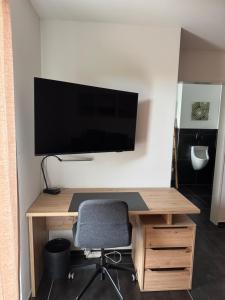 a desk with a television on a wall with a chair at Comfort Rooms mit Whirlpoolzugang in Romanshorn +7 photos