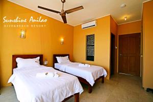 two beds in a room with yellow walls at Sunshine Anilao Dive and Beach Resort in Batangas City
