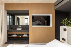 a bathroom with a sink and a tv on a wall at Anasa Luxury Resort in Elaiokhórion