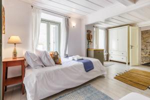 a white bedroom with a large bed and a desk at La Casa Del Limon - Sea Views & Walkable Location in Skopelos Town