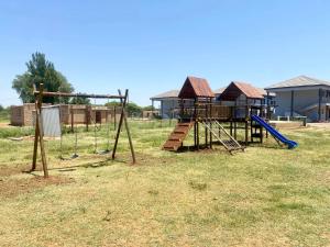 a playground with a swing set in a field at Nandi Gosa Apartments in Mahikeng