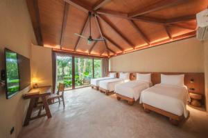 a room with four beds and a desk and windows at Kira Baya Koh Samed in Ko Samed