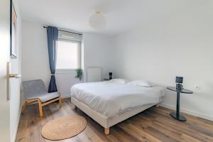 a bedroom with a bed and a chair and a window at Appart' du Trident in Mulhouse
