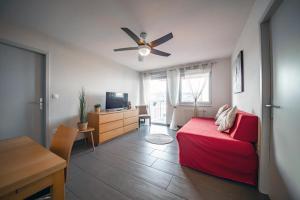 a bedroom with a red bed and a ceiling fan at Appart' du Trident in Mulhouse