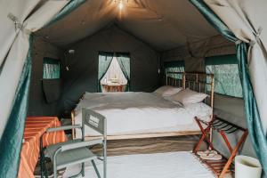 a bedroom in a tent with a bed and a chair at Bunduz Mara in Sekenani