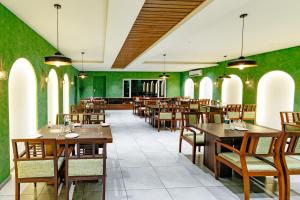 a restaurant with wooden tables and chairs and green walls at Hotel Lals Residency, Adoor in Adūr