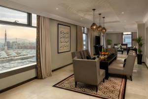 a dining room and living room with a dining table and chairs at Sofitel Shahd Al Madinah in Medina