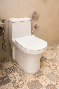 a white toilet in a bathroom with a tile floor at Cherrywood at Rajpur Road by Zenvana in Dehradun