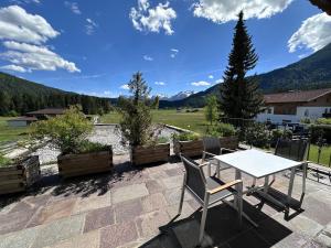 a table and chairs on a patio with mountains in the background at Chalet Cristall Superior Appartement 7 in Leutasch