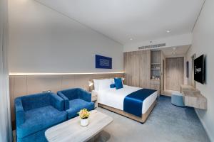 ein Hotelzimmer mit einem Bett und einem blauen Sofa in der Unterkunft Kingsgate Hotel Clock Tower in Dubai