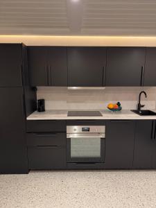 a kitchen with black cabinets and a stove and a sink at Pool & Sauna Retreat - Private Studio Apartment Porsgrunn in Porsgrunn