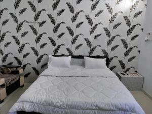 a bedroom with a white bed with a black and white wall at Surya hotel in Gangāpur