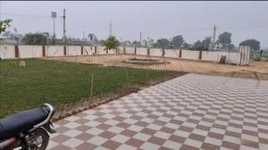 a motorcycle parked next to a field with a fence at Surya hotel in Gangāpur