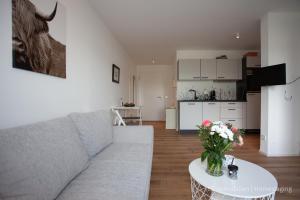a living room with a couch and a table with flowers at Seensucht in Bodman-Ludwigshafen