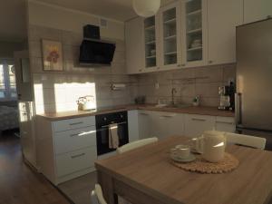 a kitchen with white cabinets and a wooden table at Apartament Secundus in Ełk