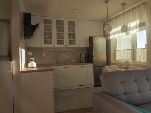a kitchen with white cabinets and a couch in it at Apartament Secundus in Ełk