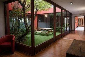 a room with glass doors with a table and a tree at Enzo Hôtels - ST Eloy Metz Amneville in Amnéville