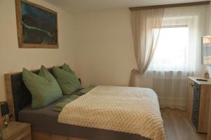 a bedroom with a bed with green pillows and a window at Appartement Naunspitzblick in Ebbs