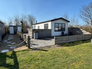 a house with a fence in front of it at Chalet 130 in Petten