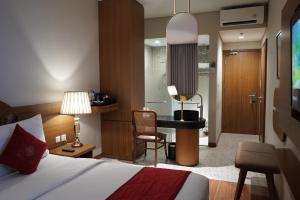 a bedroom with a bed and a desk with a chair at Ramada by Wyndham Yogyakarta in Yogyakarta +291 photos