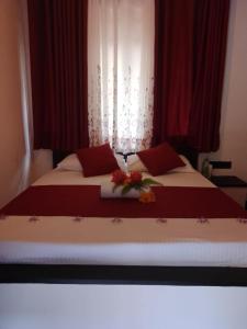 a bed with red pillows and flowers on it at George Bungloaw in Henegama