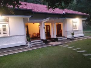 a small white house with a porch at George Bungloaw in Henegama