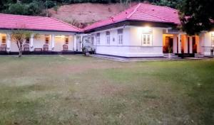 a white house with a red roof and a yard at George Bungloaw in Henegama