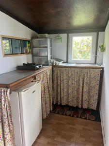 a kitchen with curtains and a sink and a window at Au pied du Piton Bellevue in Sainte-Rose +6 photos