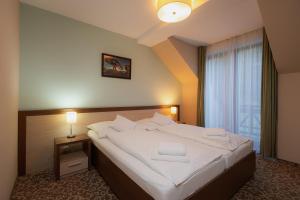 a bedroom with a large bed with white sheets at Hotel Green in Dolný Kubín