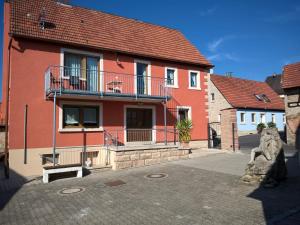 uma casa vermelha com uma varanda numa rua em Atelier Reinhart em Rauhenebrach