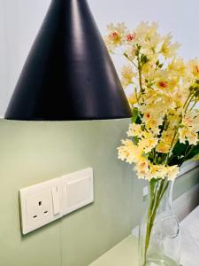 a vase of flowers on a table next to a light switch at The Dutch Station Hotel in Ambalangoda