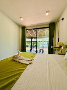 a large bed with a green blanket on top of it at The Dutch Station Hotel in Ambalangoda