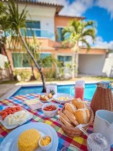 a table with breakfast food on a table in front of a pool at Pousada Casa de Praia in Marechal Deodoro