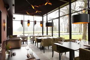 een restaurant met tafels en stoelen en grote ramen bij Hotel Restaurant Het Witte Paard in Delden