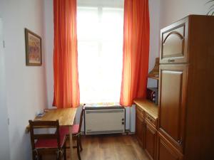 eine Küche mit einem Tisch und ein Fenster mit orangefarbenen Vorhängen in der Unterkunft Apartment Harmonia in Franzensbad