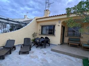 a patio with chairs and a table and a building at Casa de playa, cerca de todo in Los Narejos