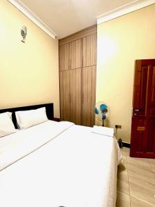 a bedroom with a white bed and a wooden cabinet at Sky world homes in Kampala