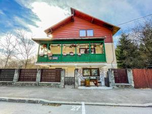 a red house with a green balcony on a street at SemiLuna in Buşteni